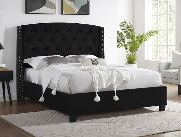 Black tufted upholstered bed frame with tall button-tufted headboard and nailhead trim in modern bedroom