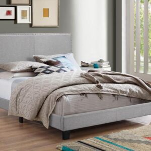 Gray upholstered platform bed frame with nailhead trim in modern bedroom setting