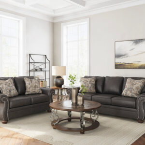 Charcoal faux leather sofa and loveseat set with rolled arms, nailhead trim, and decorative accent pillows